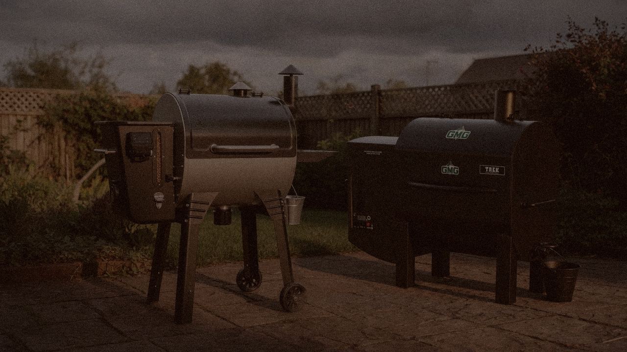Camp Chef Woodwind WiFi 24 and Green Mountain Grills Trek at night with smoke, wood pellet grills on a dark patio