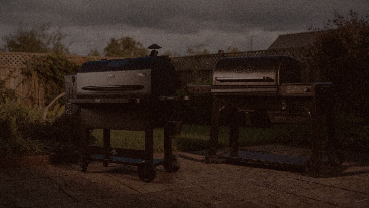 Green Mountain Grills Peak and Traeger Ironwood at night with smoke, wood pellet grills on a dark patio