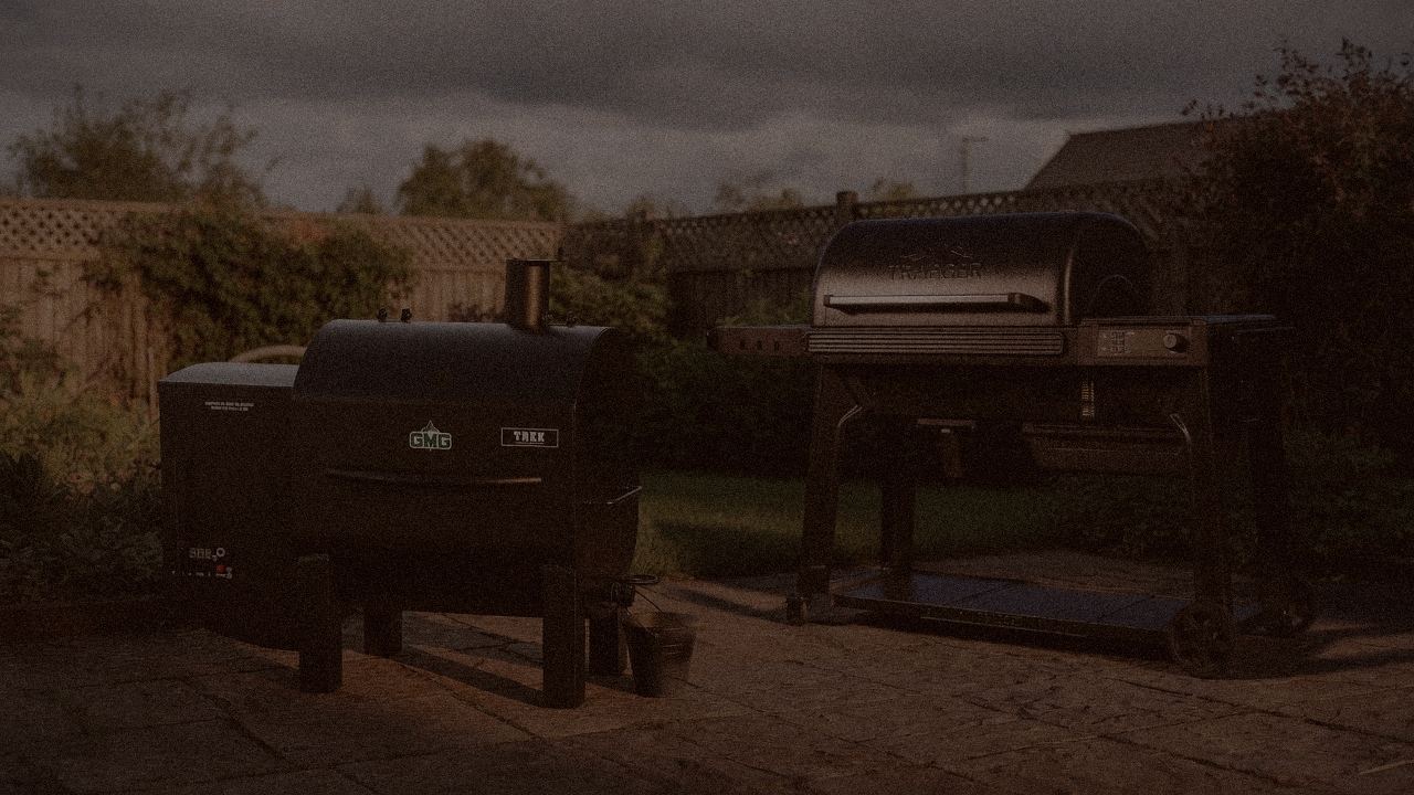 Green Mountain Grills Trek and Traeger Pro 780 at night with smoke, wood pellet grills on a dark patio
