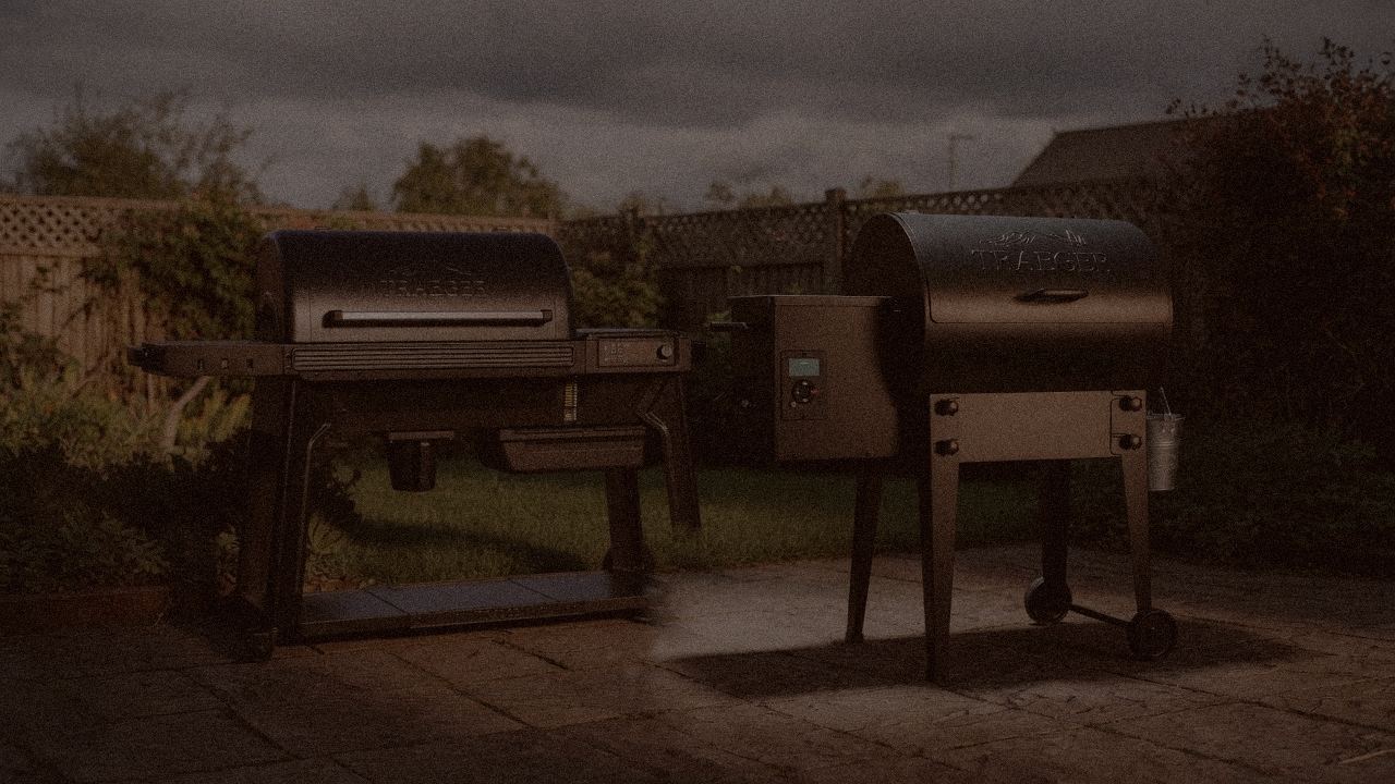 Traeger Ironwood and Traeger Tailgater 20 at night with smoke, wood pellet grills on a dark patio